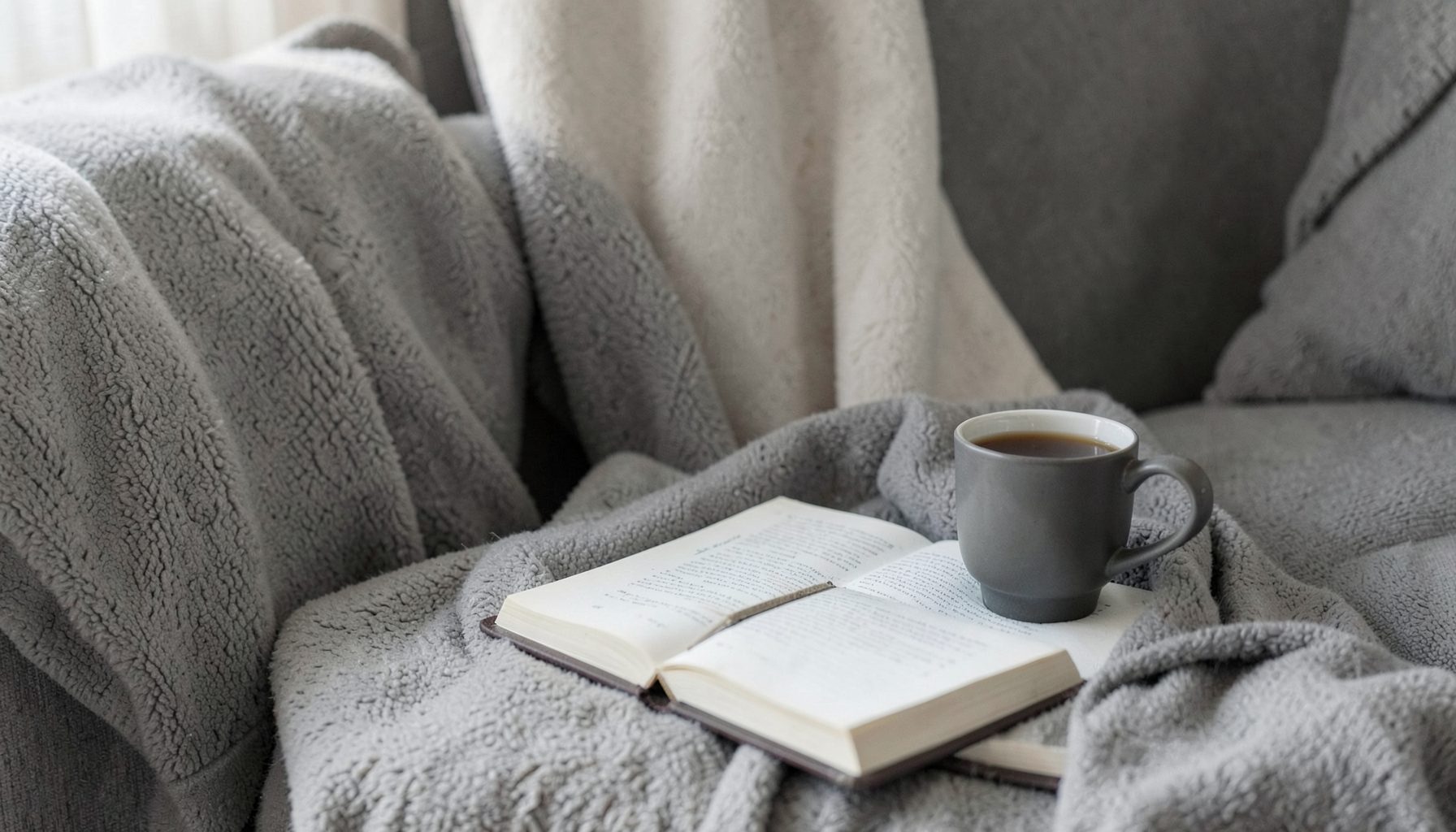 Cozy living room corner with a journal and cup of tea, soft charcoal and cream tones
